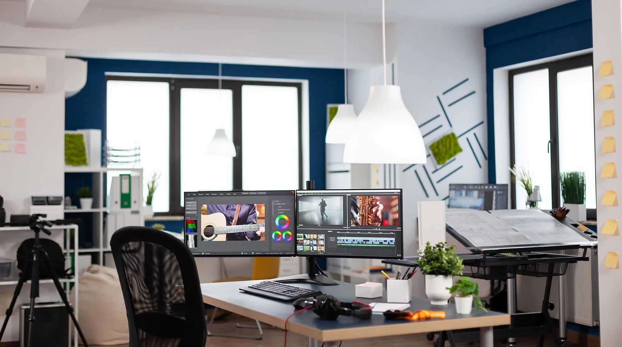 Empty modern creative agency office with dual monitors setup with processing video film montage. Video editing start up studio company with no people in it and post production software on pc displays